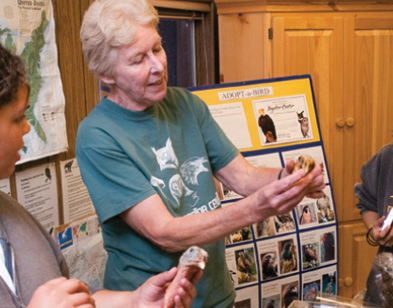 o Cowen, long-time volunteer and education program coordinator, explains raptor anatomy to center visitors. For 30 years she has conducted on-site presentations for visiting classrooms and other groups.