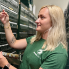 A person standing in front of a card file cabinet looking at a microscope slide.